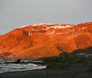 Sunrise over the plateau turning a mountain orange on Macquarie Island