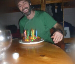 Stephen celebrating a birthday in the field. Expeditioner with birthday cake in hut