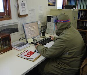 Matt, dressed in a coverall with goggles, checks figures on a computer