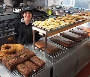 Maria the chef poses with trays of cakes and biscuits baked today