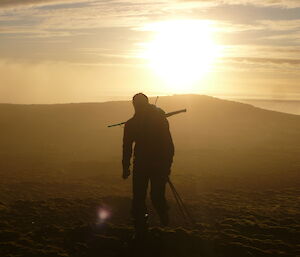 Hunter walking with sunset in background