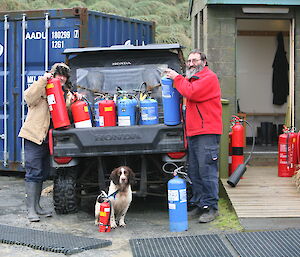 two expeditioners and a dog standing by a ute