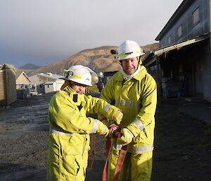 Two expeditioners dressed in yellow fire fighting suits with hoses