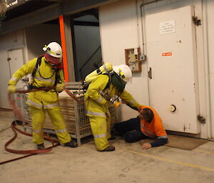 Two expeditioners assisting another during fire fighting training
