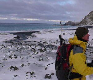 Dave B on snowy beach with yellow jacket and walking poles