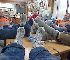 Expeditioners in a group with their feet (in socks) on a table