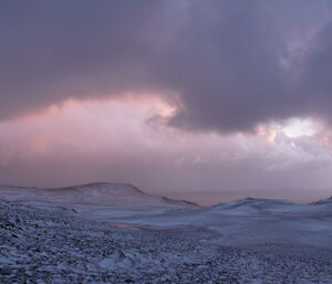 Landscape shot of snow and horizon, clouds in sky and a purple cast over all