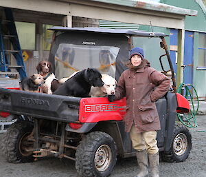 Jane poses with a small truck and a flatbed full of dogs