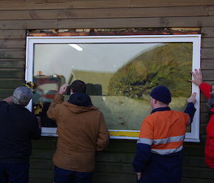 Four expeditioners inspect a new window