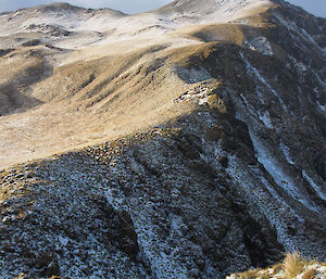 Sun on west side of grassy peaks