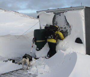 Karen digging through a crust of ice and snow for the door of a hut