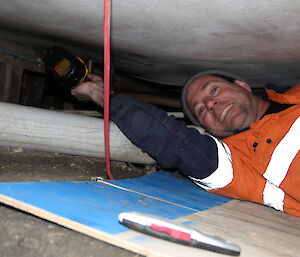 Tom working on the ground underneath a building