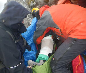 Kelly’s mock broken leg is secured by other expeditioners