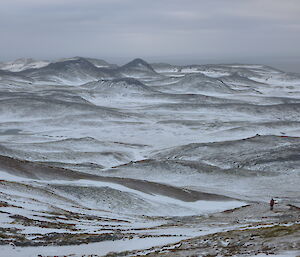 Expeditioner poses alone in vast snow-dusted Macquarie Island Landscape