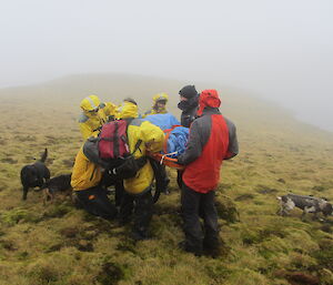 A group of expeditioners move a faux patient during SAR training