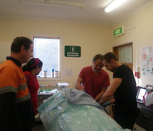 Tom, Andrew and Jim settling mock patient Ray, Dr Mel looks on