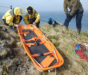 Expeditioners conducting search and rescue training in the Macca landscape with stretcher in foreground