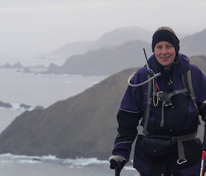 Dana poses on a cliff with sea in background