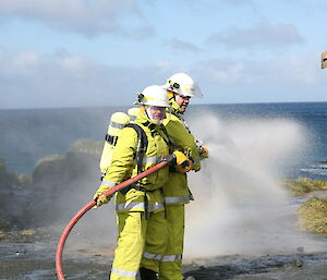 Jim and Tom practice using the fire hose