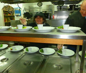 Chef Maria and assistant Dave B plating food in the kitchen