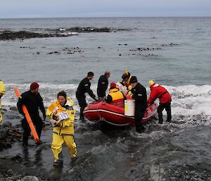 Unloading cargo from inflatable boat onto the rocky beach