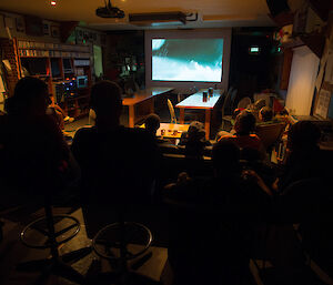 Expeditioners watch a movie on a projector