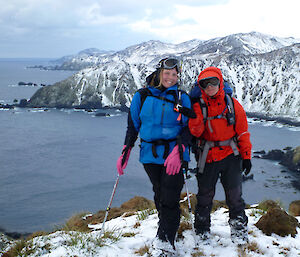 Jaimie and Anna, albatross researchers, pose on snowy cliff with water in background