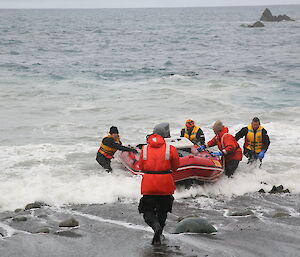 Arriving at Hurd Point, expeditioners help ground the boat full of supplies on the beach
