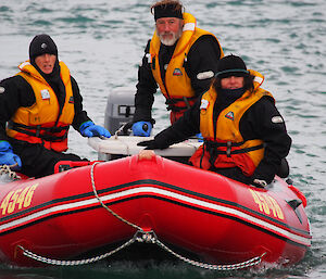 Three people in a zodiac inflatable boat.