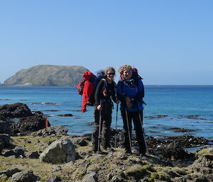 Anna and Jaimie standing on a rocky/mossy beach with water behind
