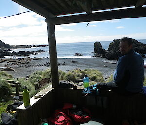 Andrew at Green Gorge hut with beach and penguins in background