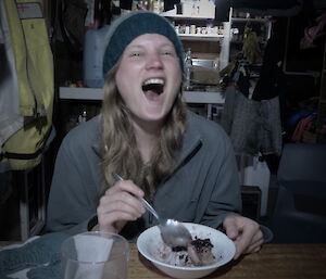 Karen inside Lusi bay hut laughing while eating chocolate cake