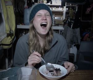 Karen inside Lusi bay hut laughing while eating chocolate cake