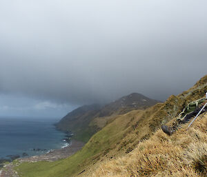 Stu stopping for a short break at Lusi bay on a hill with ocean and landscape making up most of the photo