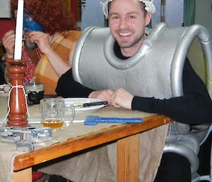 Andrew in dinner attire, dressed in a silver foam tunic with what appears to be an imitation viking cap with silver horns