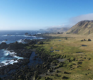 Long shot of Aurora Point landscape, sea on left and plateau ending in mountain ranges on right