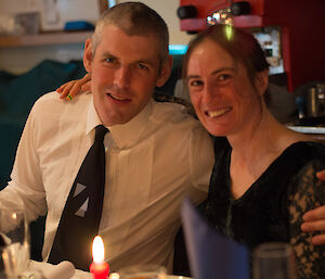 Pete and Jane with arms around each other face the camera at Christmas dinner