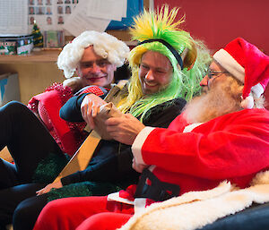 Santa and Mrs Claus giving Andrew his present — Andrew sits between them wearing a green and gold with with spikes