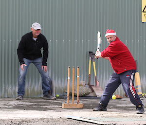 Jim wearing santa hat takes a swing at the ball