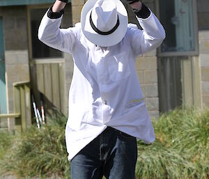 An expeditioner dressed as a cricket umpire with white coat and hat, head down
