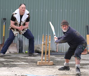 Gaz takes a swing at the ball during a game of cricket while Jack waits to catch the ball behind the stumps