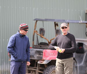 Paul and Dave, who is holding the game ball, talk during a game of outdoor cricket