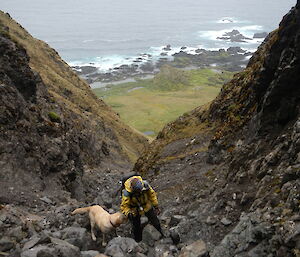 Female expeditioner and her labrador walking up a steep gully