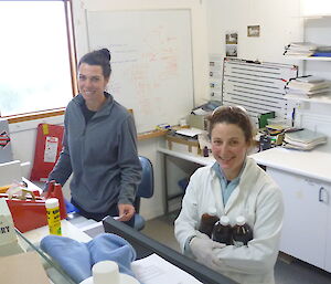 Two female expeditioners standing behind a bench in the science lab