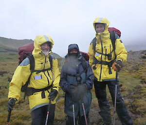 Three expeditioners in the field with packs on posing for camera