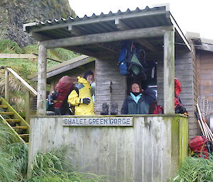 2 expeditioners standing out the front of green a hut