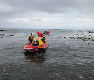 Two inflatable boats on the water taking people, dogs and gear to a field hut