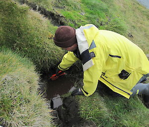 Expeditioner kneeling down replairing a water pipe