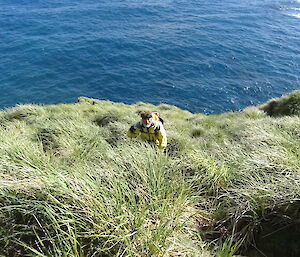 Expeditioner climbing up a steel coastal grassy slope