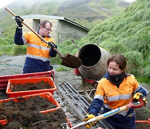 Two expeditioners placing dirt into plastic bins